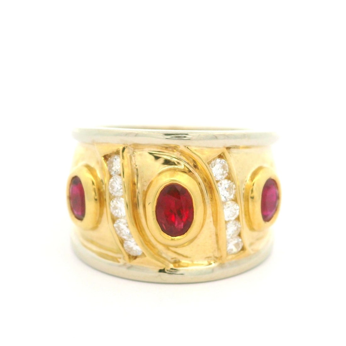 18K Two Tone Gold Band Ring with 1.60ct Oval Ruby and Diamonds: 18K Two Tone Gold Band Ring with 1.60ct Oval Ruby and Diamonds This stunning 18k two-tone gold band ring features a captivating bezel set oval ruby and sparkling diamonds. The vivid red ruby, weighing