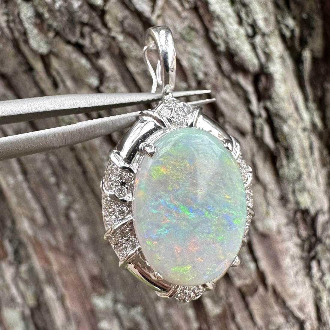 White Gold Opal Pendant with 32 Diamond Enhancer: White Gold Opal Pendant with 32 Diamond Enhancer Pre-owned women's enhancer pendant featuring a natural oval cabochon opal with a white base and a nice play of mixed colors, accented by natural round 