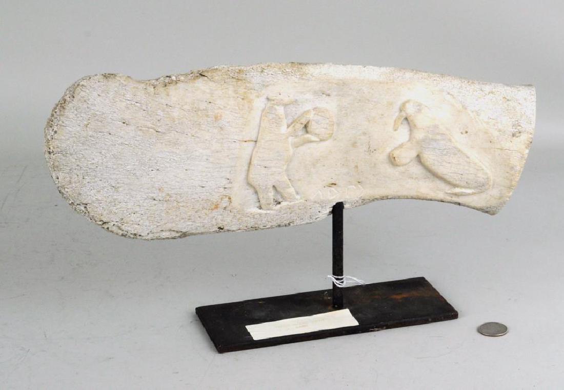 Signed Inuit Carved Fossilized Whalebone Sculpture: Signed Inuit carved fossilized whalebone sculpture, double sided, carved with animal and hunt scenes, signed initials "ADM". Wear and losses as shown. 9" high, 16" wide overall. Provenance: Property o