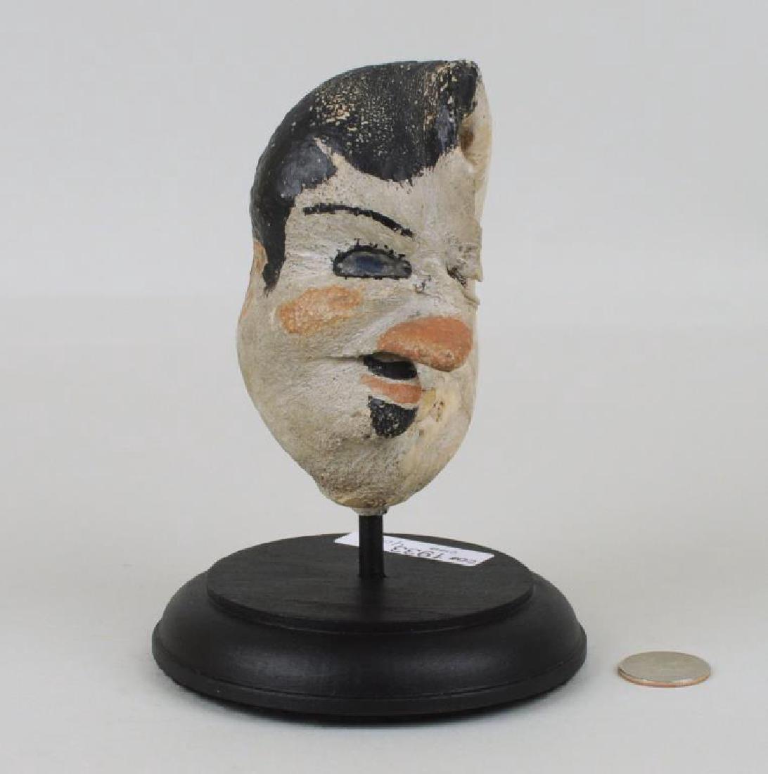 American Folk Art Painted Whale Ear Bone: depicting a man's face mounted on wood stand. 6 1/2" high, 4 1/2" wide.