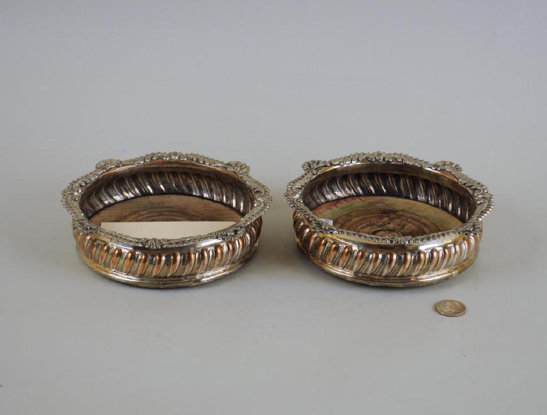 Pair Sheffield Rococo Wine Coasters: plate wear, loss; finish wear, loss, cracks to wood. 2" high, 6 3/4" diameter. Provenance: Property of a New York lady.