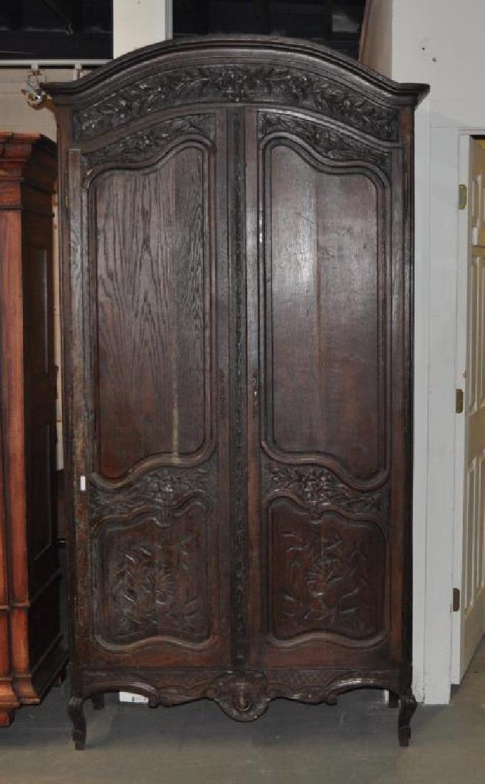 French Provincial Carved Oak Armoire: having a shaped cornice over floral carved crest, florally carved paneled doors, interior with five adjustable shelves. Finish wear, loss, age cracks, soiling, mildew. 90 1/4" high, 44" wide, 17 1/2" 