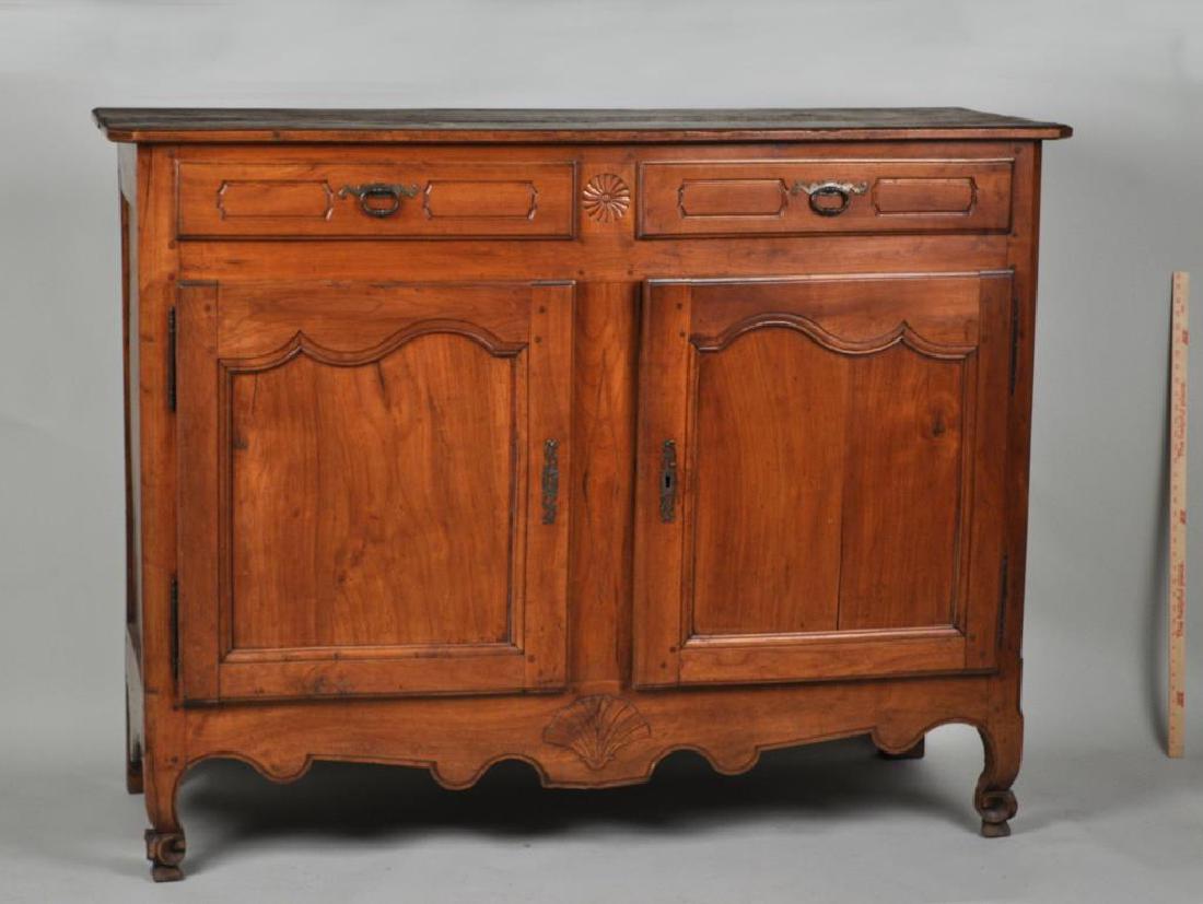 French Provincial Carved Cherrywood Buffet: 18th century, with two drawers above two paneled doors, removable with barrell hinges, set on scrolled feet, with losses, worming, and old repairs. 48" high, 62" wide, 22" deep.