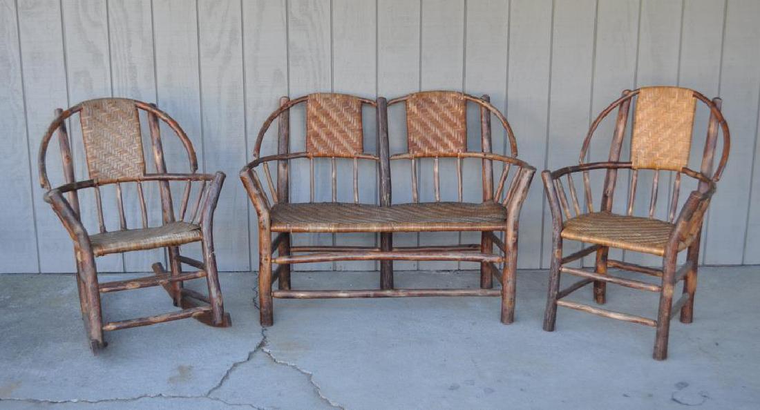 Three Piece Adirondack Furniture Set: comprising a settee, rocker and armchair, probably by Hickory Furniture Co. Finish wear, loss, cracks, losses. Largest: 35 1/2" high, 48" wide, 17 1/4" deep.