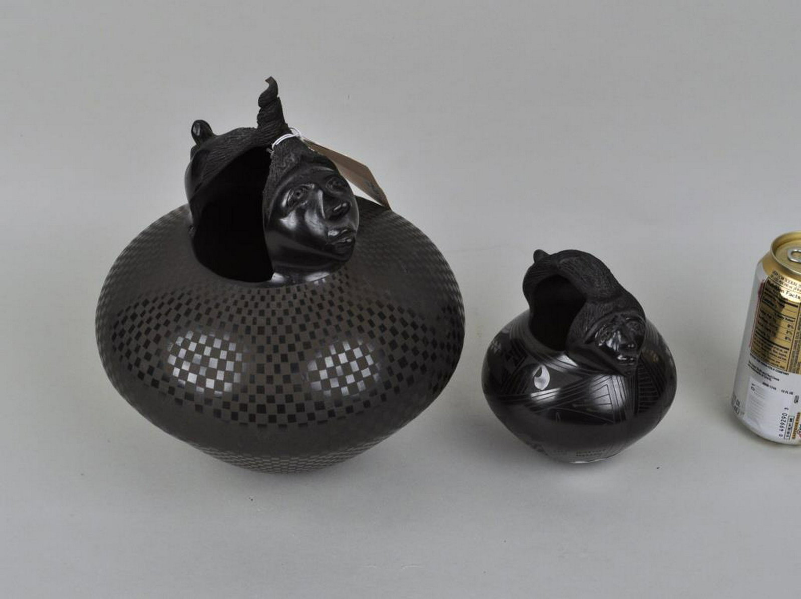 Two Hector Ortega Sculpted Blackware Pottery Jars: formed with steep walls, scratch decorated overall with juxtaposed human face handles, both signed on base "Hector Ortega". Largest: 9" high, 8" wide. Provenance: Property of a Madison CT Estate.