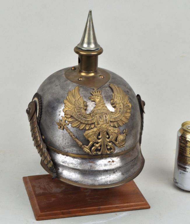Prussian Steel/Brass Military Helmet: Kurassier lobster tail pickelhaube, now mounted on a wood stand. 14" high (overall), 8" wide, 12" deep. Old cleaning leaving fine scratches to surface, damage to liner and strap. Provenance: Property 