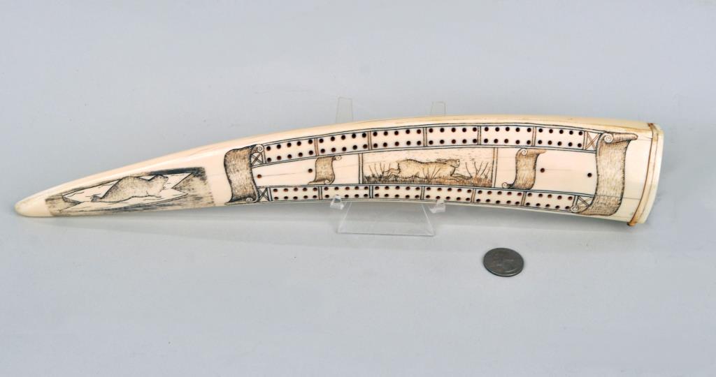 Inuit Scrimshaw Walrus Tusk Cribbage Board: depicting a hunter and prey. 2 1/2" wide, 15 1/4" long. Age cracks, hole verso, perhaps for mounting on stand. Provenance: Property of a New Haven County CT Estate.