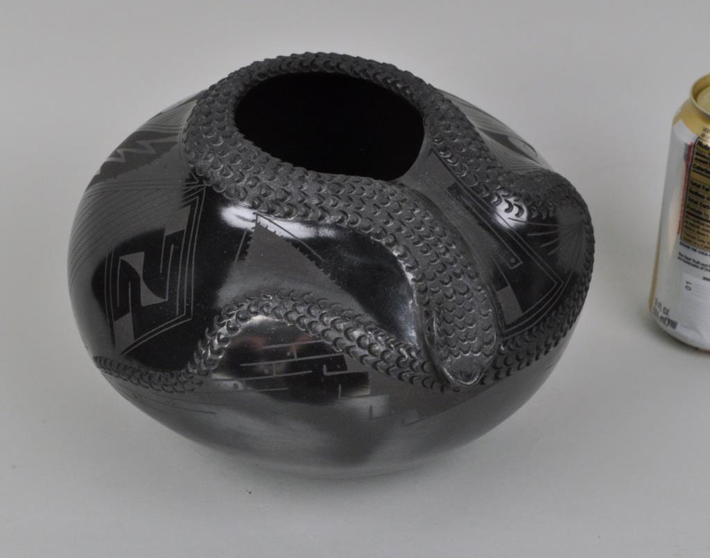 Mata Ortiz Sculpted Blackware Pottery Jar: ovoid form with scratch decoration and upper portion of jar decorated in relief with a human face and a rattlesnake; signed on base "Orlando al Quezada". 6" high, 9" diameter. Provenance: Property of 