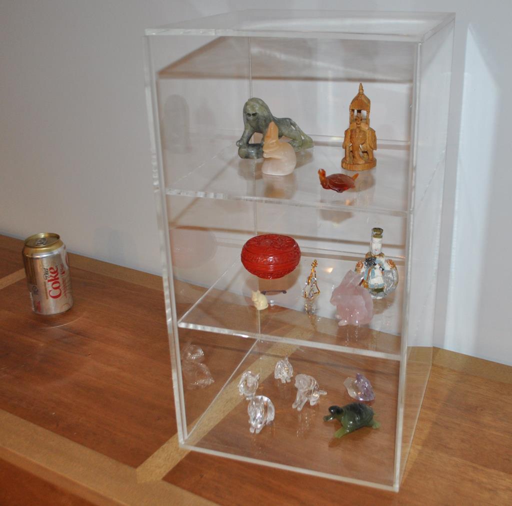 Collection Fifteen Mostly Asian Curiosities: including four carved rock crystals, an amethyst carved animal, polychromed snuff bottles and other items, all in a plexiglass case. Some with chips and losses. Largest: 1 3/4" by 3" diameter; case 18