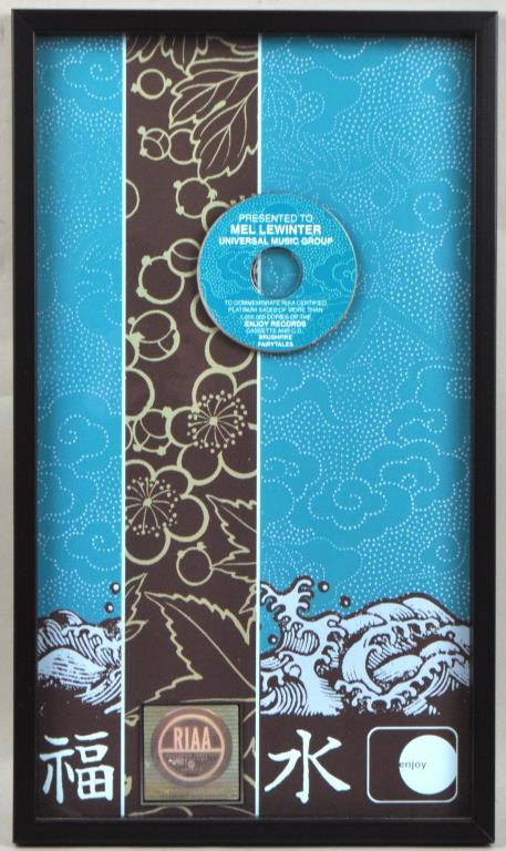 Jack Johnson RIAA Platinum Award w/Autograph: RIAA sales award for "Brushfire Fairytales" with autograph note taped verso. 24" high, 14" wide. Not examined out of frame. Provenance: Shagbark Farm, Party Barn, Washington CT.