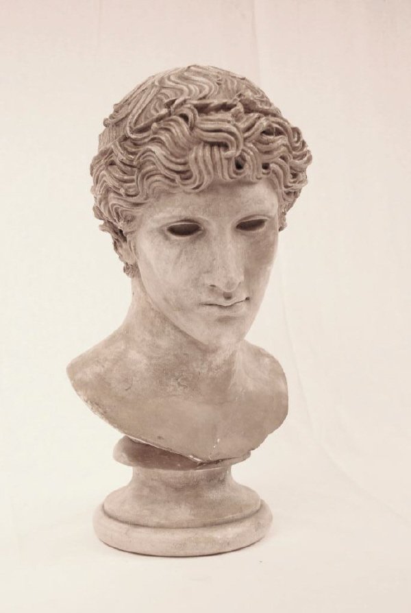 Plaster Bust of Young Greek God: Plaster bust of young Greek god on socle. Repair at attachment and other old repairs. 15" high.