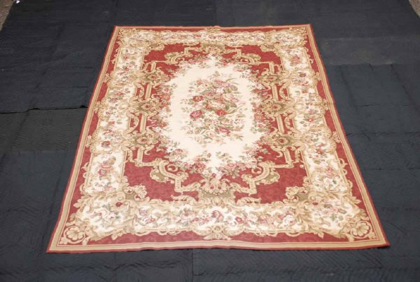 Handmade Needlepoint Rug: Handmade needlepoint rug/wall hanger made in the USA, Durham NC. Light burgundy center field with beige border of florals sewn in two sections. In good condition. 103" long, 66" wide.