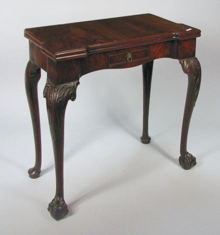 Irish Chippendale Card Table, 18th C.: Very fine Irish George III carved mahogany fold over game table with shaped top, with crotch veneered top surface opening to a baize lined top with square candle notches and game pockets, with a figur