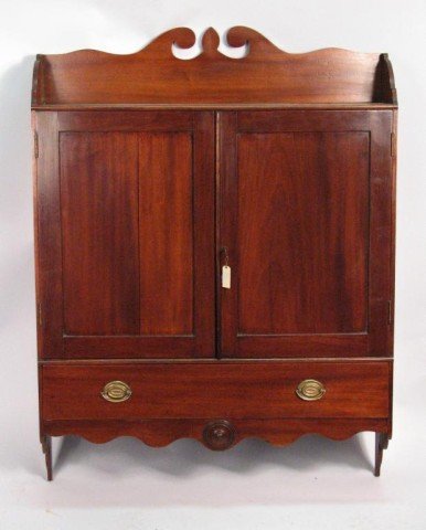 Federal Mahogany Hanging Cupboard, 19th C.: Federal carved mahogany hanging wall cupboard, with scrolled top and two doors. Probably New York, circa 1815. 41" high, 32" wide, 7" deep.
