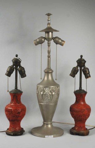 Group of Three Lamps, One Art Deco Form: Art Deco form lamp, together with a pair of cinnabar lamps. 26" high (to finial), 8" diameter. Cinnabar lamps 18" high (to finial), 4" diameter. Provenance: A California private collector.