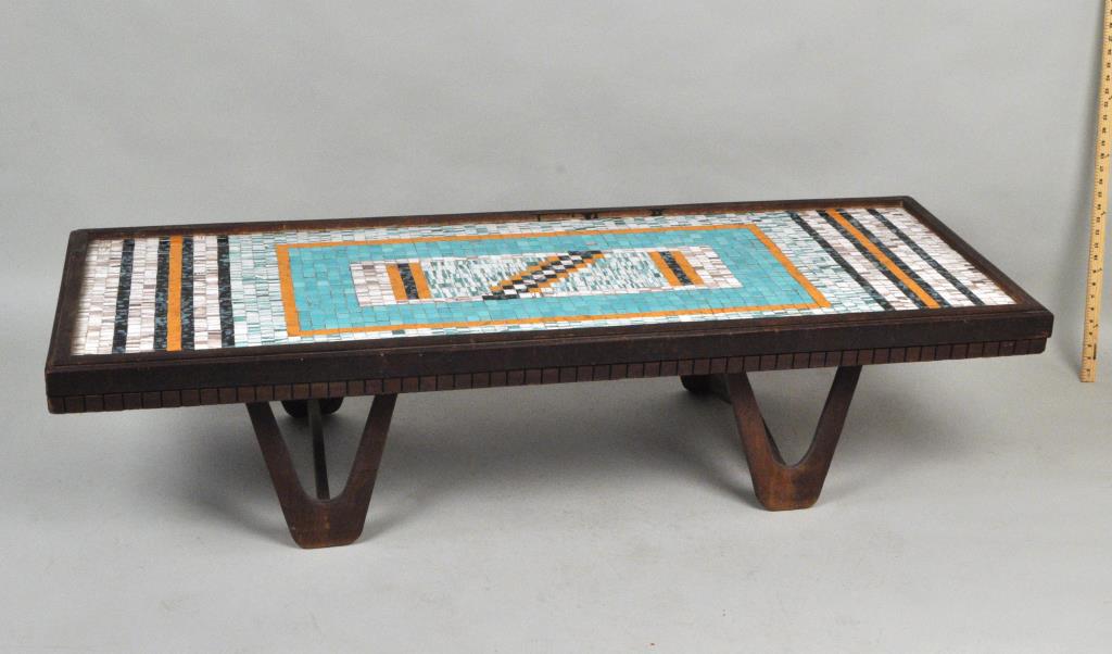 MCM Mosaic Tile Top Wood Coffee Table: with geometric designs in orange, aqua, blues and browns. 15" high, 23" wide, 62 1/2" long. Wood with finish wear, loss. One aqua tile missing, a few with cracks, small glaze chips.