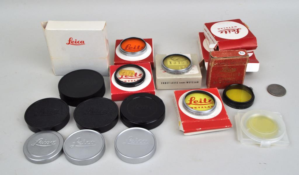 Group of Leica Lens Caps & Accessories: including three metal and four plastic Leica rear lens caps, Leica Gelbfilter 2, four Leitz Wetzlar filters and boxes, and one Argus filter. All in estate condition. Largest: 2 1/4" diameter. Provenan