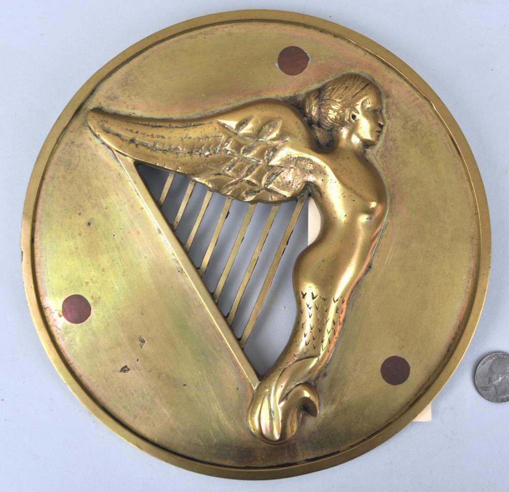 Round Brass Ship's Badge "Irish Harp": possibly "HMS Hibernia". 8 1/2" diameter. Light wear, oxidation, three plugs, some edge dents. Provenance: Estate of George E. Ratcliffe, Darien, CT. We offer in-house packing and shipping of this ite