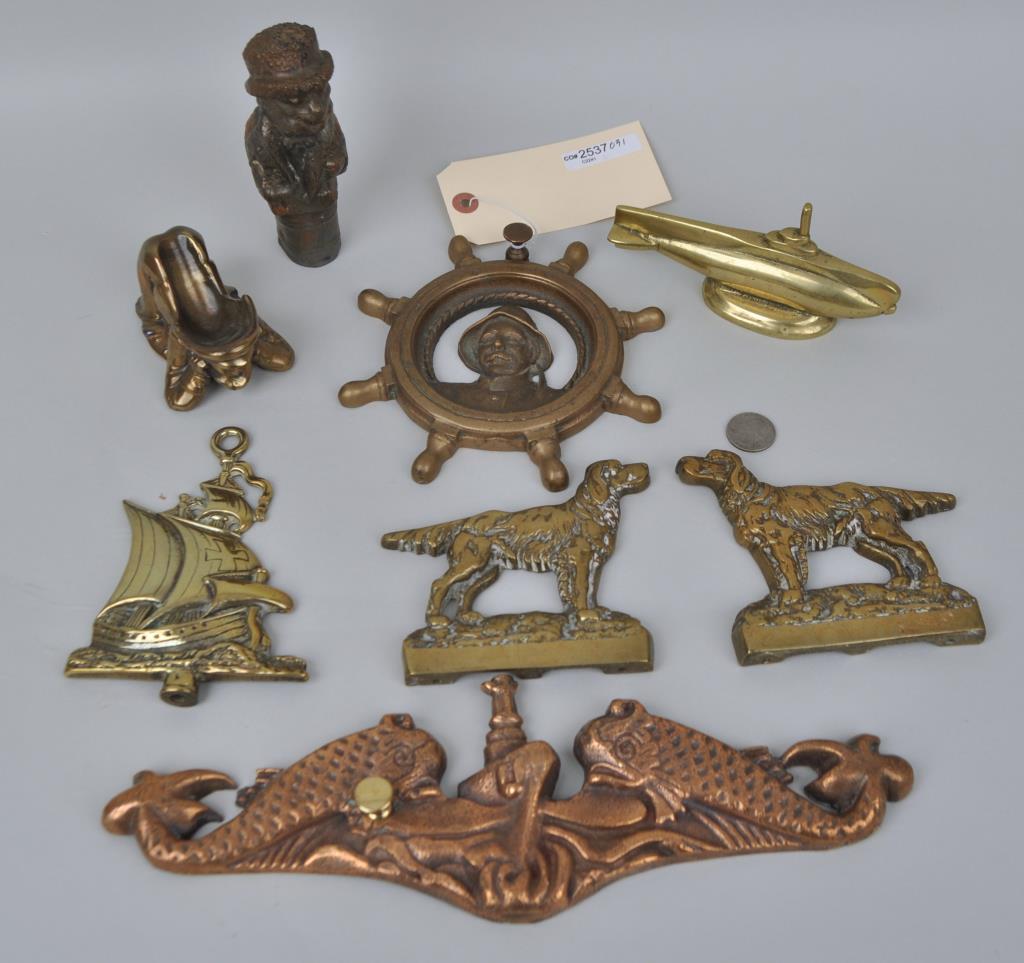 Group Eight Brass Mostly Nautical Accessories: including a dolphin mount, submarine paperweight, ships' wheel portrait plaque, etc. Largest: 4 1/4" high, 13" long. Slight surface wear to some. Provenance: Estate of George E. Ratcliffe, Darien, CT.