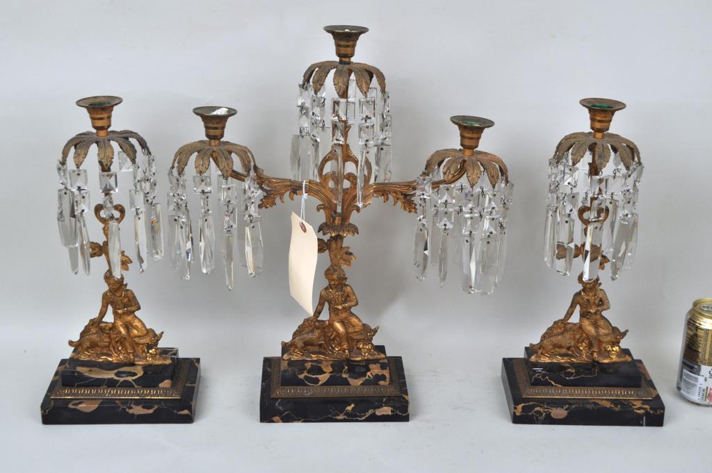 Classical Gilt Brass Three Piece Garniture Set: featuring a boy with a dog. Largest: 18" high,15" arm to arm, base measures 7" wide, 4.75"deep. Crystals have some chipping, two crystals are missing large drops. Provenance: Property of a Massachuset