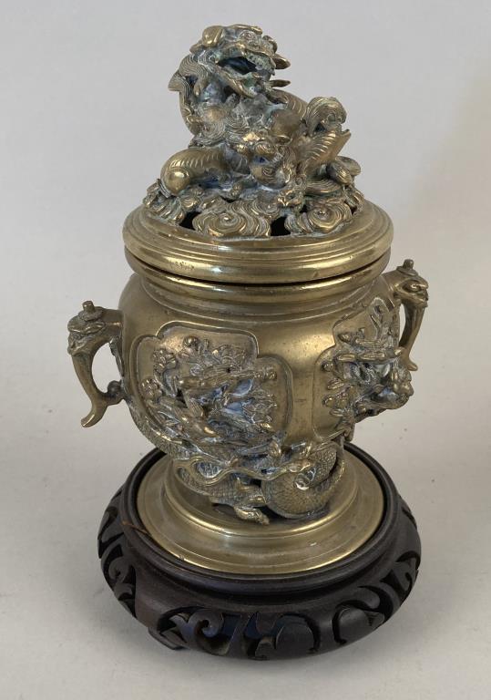 Chinese Brass Lidded Censer/Carved Wood Stand: with Buddhist lion and cub finial, dragon design body with figures cast in relief, signed on base. 8 1/2" high, 5" diameter. Property of an Essex CT estate.