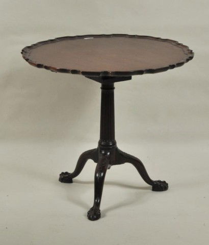Chippendale Carved Mahogany Piecrust Table: Chippendale carved mahogany piecrust tilt-top tea table, the circular top with shaped, molded edge tipping and turning on a birdcage support over a fluted columnar standard, raised on a tripod base of
