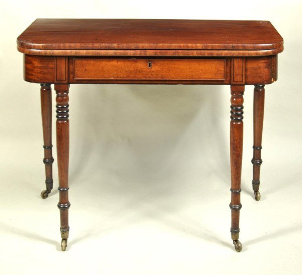 Sheraton Mahogany Card Table, 19th C.: Sheraton mahogany flip top game table with double gates and later drawer, turned legs with ebonized rings and original brass cup casters. England, early 19th century. Break in right apron, crack in lo