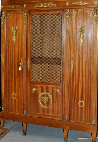 Empire Style Bronze Mounted Bibliotheque: Empire style ormolu mounted mahogany bibliotheque, with flat molded cornice over a frieze above three doors, the central door with wire mesh panel, set on a base with square tapering legs with brass p