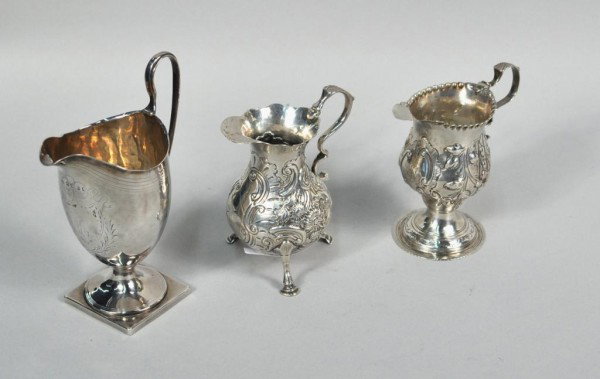 Three Georgian Silver Cream Jugs: Three Georgian silver cream jugs, the first by Robert and David Hennell, London, 1815, of helmet form, on square base, the second by Joseph Mumford, London, 1752, of drop belly form, on three hoof fee