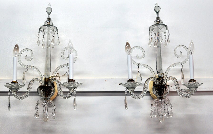 Pair of George III Style Two Arm Wall Sconces: Pair of George III style crystal wall sconces with spire top section above double curved sconce arms, all with crystal bobeches and depended prisms. 20th century. 25" high, 15" wide, 8 1/2" deep.