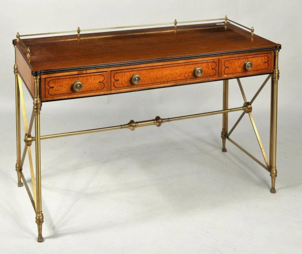 Regency Style Brass Mounted Inlaid Writing Table: Regency style brass mounted inlaid satinwood writing table, with brass gallery and ebony inlays, set on a tubular brass base with paw feet, mid 20th century. 30 1/2" high, 46 1/2" wide, 21 3/4" deep.