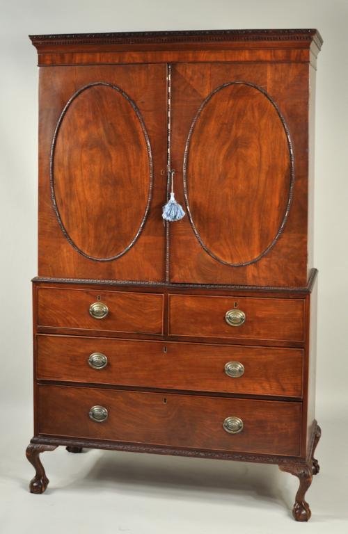 George III Carved Mahogany Clothes Press: Late George III carved mahogany clothes press, with detailed cornice above inset paneled doors with figured mahogany veneers and carved outline, having two short drawer over two graduated drawers and 