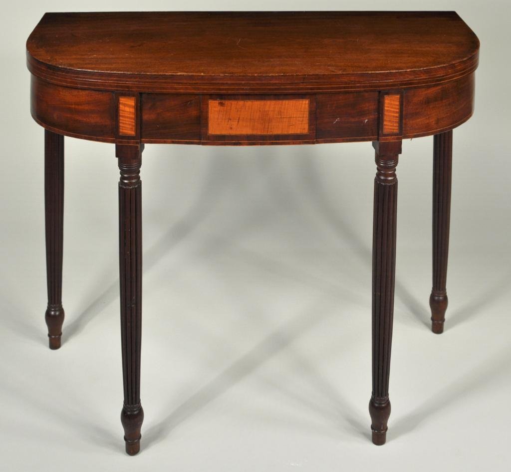 American Sheraton Carved Mahogany Game Table: Sheraton carved and inlaid mahogany game table, of "D" shape with reeded top edge, figured mahogany apron with inset panel of tiger maple, the turned and reeded legs also with tiger maple panels and e