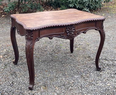 Continental Carved Rosewood Writing Table, 19th C.: with four serpentine sides with gadrooned carved top, apron with bead and rosette carving and large leafage carved ornament, one side fitted with two working drawers. 27.5" high, 44" wide, 28" deep. A