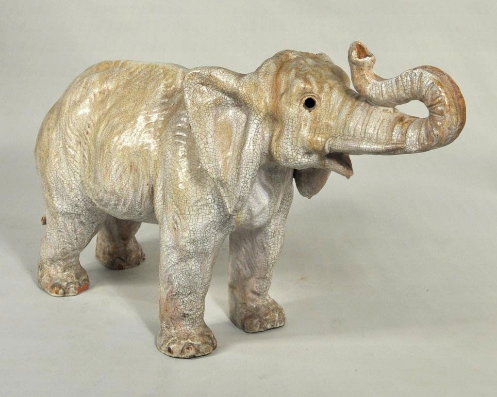 Very Large Crackle Glazed Earthenware Elephant: Very large crackle glazed earthenware elephant, well modeled, standing with head raised, old repair to one ear, discoloration and small areas of loss to glazed surface. 27" high, 44" wide, 13" deep