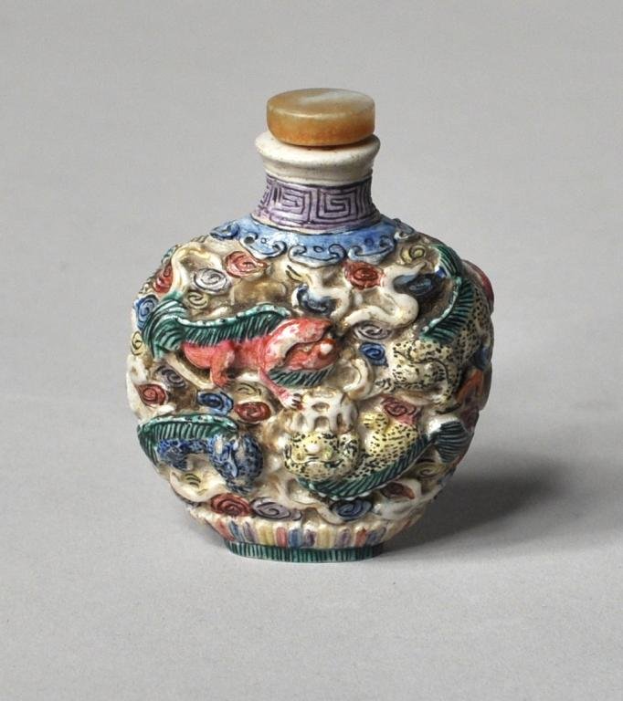 Asian Painted Porcelain Snuff Bottle: Asian painted porcelain snuff bottle decorated with foo dogs and leopards in relief, with chipped stopper. 2" high, 3 3/4" diameter