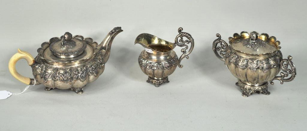 Continental Silver Three Piece Tea Set: Continental silver three piece tea set, German or Austrian, 19th c., comprising teapot, creamer and covered sugar bowl, each of squat melon form, chased with foliage, with pomegranate finials, the pot