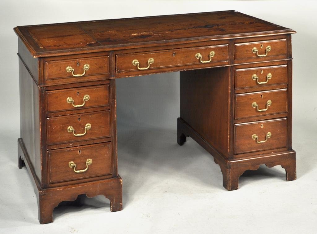 George III Style Leather Top Writing Desk: George III style mahogany pedestal form writing desk with leather top, one central long drawer flanked by two banks of drawers and doors, set on a bracket footed base. 30 1/4" deep, 54" long, 29" high
