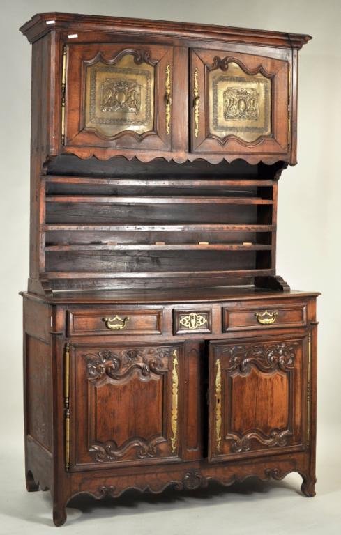 French Provincial Carved Oak Two Part Vaisselier: French Provincial carved oak two part vaisselier, the upper section with stepped cornice above two doors with leather panels bearing armorial crests over shelves; the lower section three drawers over 