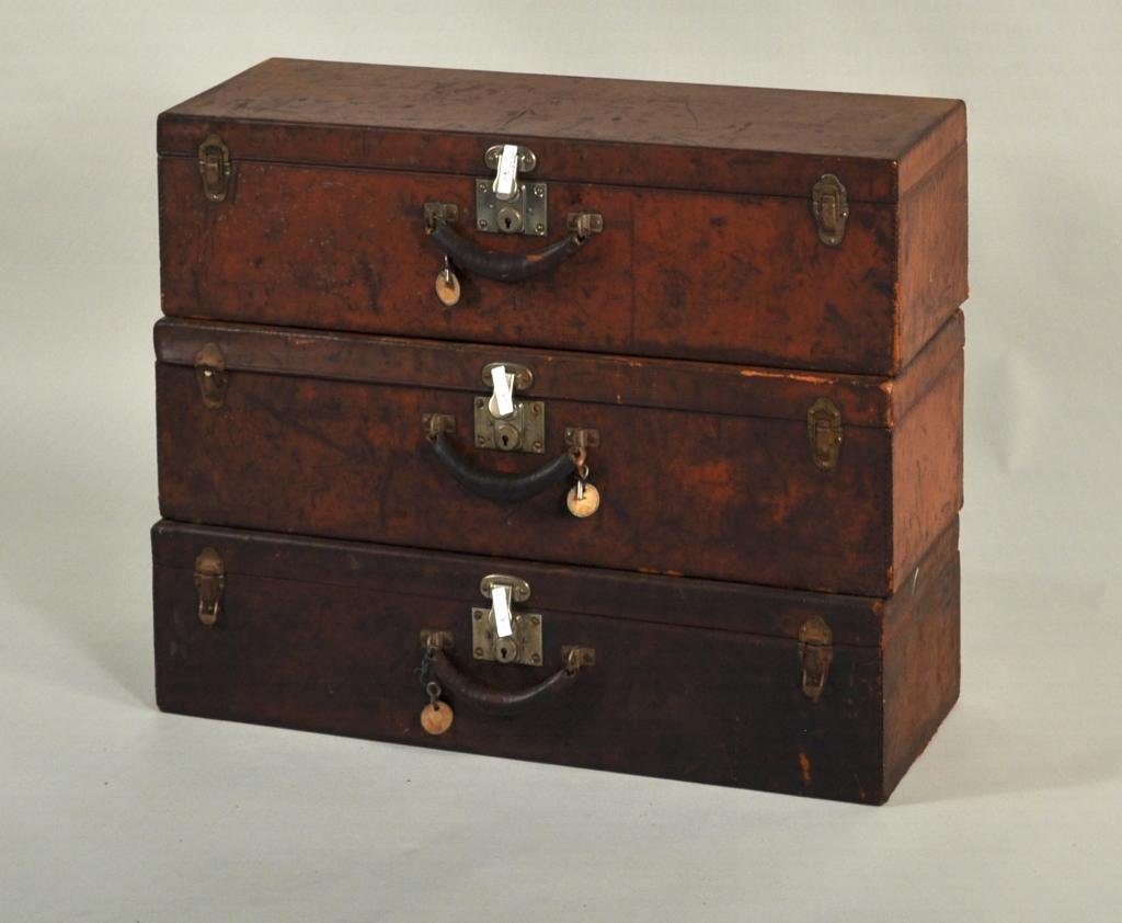 Three Vintage Leather Traveling Cases: Three vintage leather oblong traveling cases, each with original key, all with scuffing and wear. Each 8" high, 29 3/4" wide, 10 1/2" deep.