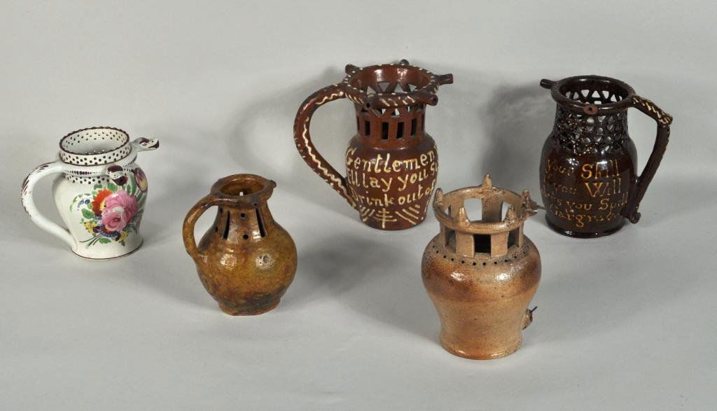 Group of Five Glazed Earthenware Puzzle Jugs: Group of five glazed earthenware puzzle jugs, various forms, two slip decorated, three dated, the smallest with old collection label, breaks and losses to two jugs. Largest: 6 3/4" high, 7 1/2" wide,