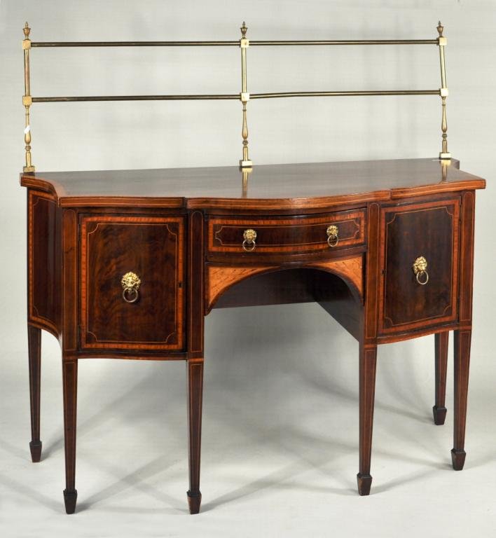 George III Style Inlaid Mahogany Sideboard: Final small George III style inlaid mahogany sideboard, with serpentine front, brass linen rail and satinwood banding, the open center section with conch inlaid spandrels. 57" high, 60" wide, 27" deep