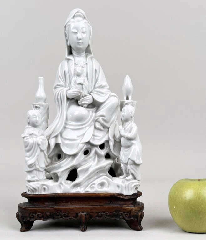 Signed Chinese Blanc De Chine Guanyin Figure: depicted seated with attendants. 10" high, 6" wide, 4" deep, excluding base. Small hairline cracks, wood chip to base.