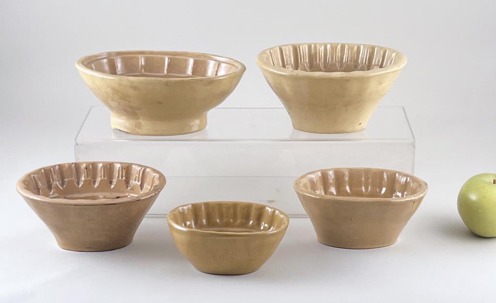Five Yellow Ware Cake Molds: largest: 5 1/2" high, 6" diameter. Chipping, crazing, age and use wear.