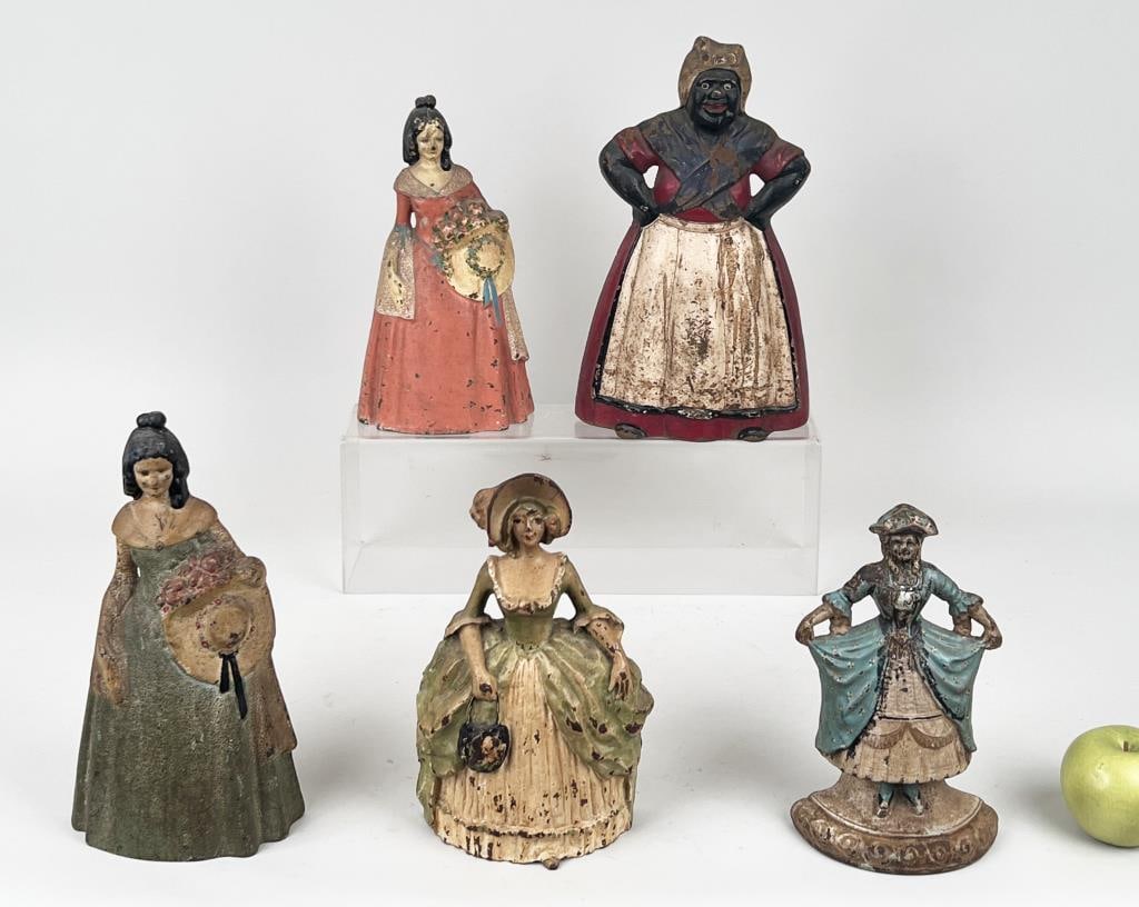 Five Large Painted Cast Iron Figural Doorstops: comprising four Southen Belle examples together with a large "Mammy" doorstop. Largest: 13 3/4" high, 8" wide, 3 1/4" deep. Paint losses, age and use wear.