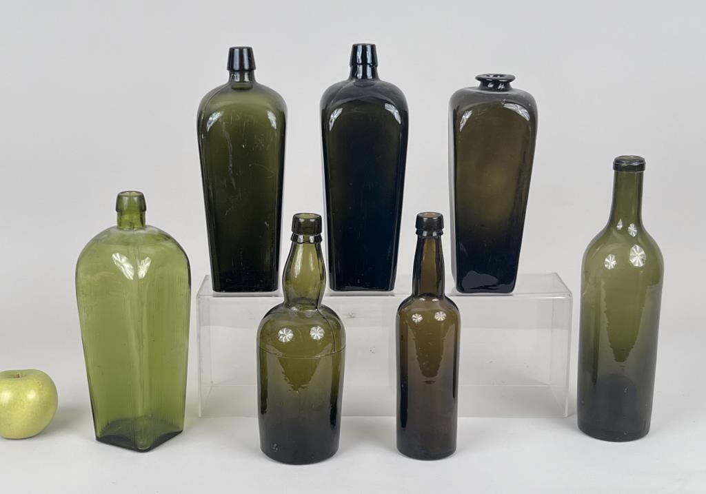 Group Seven Green Glass Bottles: largest: 10" high, 4" wide, 3 3/4" deep. Minor scratching, age and use wear.