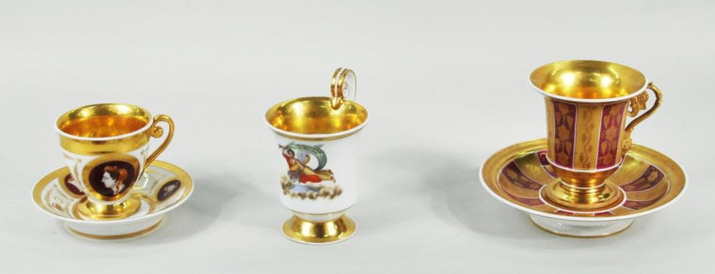 Two Porcelain Enameled & Gilded Cups: Two porcelain enameled and gilded cups and saucers, together with a single cup, 19th C, including a KPM cup with the inscription "Mit Blumen Bestraut, Sei Dein Leben!" 3" high, 3 1/2" wide to 6 1/4" d