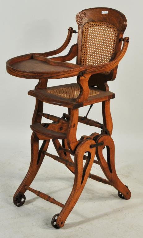 Oak Caned Seat Child's High Chair: Oak caned seat child's high chair with carved crest. 40" high, 16 1/4" wide, 22" deep.