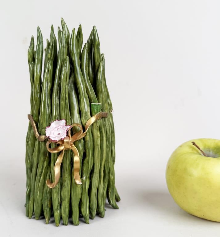 Katherine Houston Porcelain Green Beans: porcelain haricot verts wrapped in ribbon with flower. Signed on base. 7 1/2" high, 3 1/2" diameter. Losses, repairs.