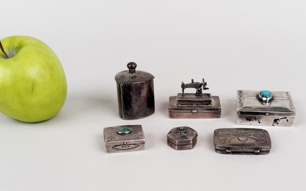Group Six Sterling Pill Boxes: comprising Native American with turquoise, miniature sewing machine, Mexican silver. Largest: 7/8" high, 2" wide, 2" deep. Gross weight: 5.385 OZT. Oxidation, use wear. Property from the Estate of Bob